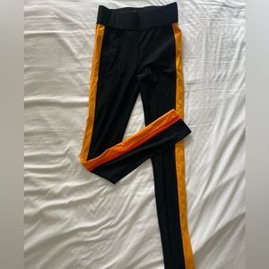 No Ka Oi black leggings with an orange striped detailing on the sides.